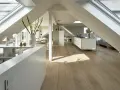 Heller, moderner spitzboden ausbauen mit Dachfenstern, offener Küche und Essbereich. Holzboden und weiße Möbel schaffen ein luftiges Ambiente.