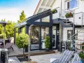 Moderner Wintergarten mit Außentreppe und Terrassenmöbeln. Ein Heizpilz sorgt für Wärme.
