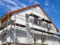 Haus mit Gerüst für Fassadensanierung. Die Kosten für eine Fassadensanierung können stark variieren.