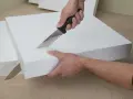 Hände schneiden mit einem Messer präzise Styropor für ein Bastelprojekt.