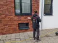 Mann reinigt mit Hochdruckreiniger die Ziegel-Fassade.