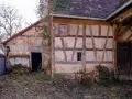 Ein altes Fachwerkhaus wartet auf seine Sanierung. Die Holzbalken und Lehmwände zeigen deutliche Spuren der Zeit.