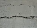Rissige Betonfassade mit sichtbarer Armierung. Die Risse zeigen die Belastung der Struktur.