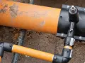 Ein orangefarbenes Rohr mit einem schwarzen Anschlussstück, das für den Gas Hausanschluss vorbereitet wird.
