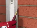 Mit einem Werkzeug wird die Fuge eines Klinkersteins bearbeitet, um ihn für das Verputzen vorzubereiten.
