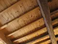 Holzbalkendecke sanieren: Alte Holzbalken und Holzbretter bilden eine rustikale Decke, die bereit für eine Sanierung ist.