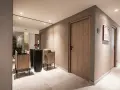 Moderner Flur mit Holztüren und einem Waschbeckenbereich. Die Wände sind mit einem rauen Reibeputz aufgetragen, der dem Raum Textur verleiht.
