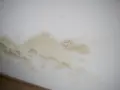Braune und gelbliche Flecken an der weißen Wand, die wie schwarze Flecken aussehen, aber kein Schimmel sind.