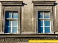 Zwei alte Fenster mit blauen Scheiben an einer verwitterten Fassade. Eine energetische Sanierung der Fenster würde sich hier lohnen.
