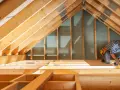 Handwerker arbeitet am Dachboden. Informieren Sie sich über die dachboden isolieren kosten, um Energie zu sparen.