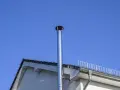 Neuer Edelstahlschornstein ragt in den blauen Himmel. Beim Schornstein bauen Vorschriften beachten für Sicherheit und Effizienz.