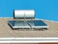 Ein pvt kollektor mit einem Warmwasserspeicher auf einem Ziegeldach unter blauem Himmel.