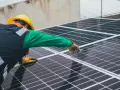 Handwerker mit gelbem Helm montiert Solarmodule für solarstrom einspeisen.