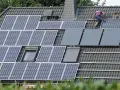 Arbeiter installieren eine PV-Anlage nach 20 Jahren auf einem Dach.