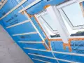 Konterlattung auf blauer Dampfbremse, die für die Dachisolierung vorbereitet wird. Dachfenster sind eingebaut.