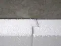 Detailaufnahme: Styrodur kleben an einer Betonwand. Die weißen Styroporplatten sind präzise zugeschnitten und stoßen nahtlos aneinander.
