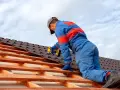 Handwerker montiert mit Akkuschrauber neue Dachziegel. Informieren Sie sich über die **Blechdach Kosten** für Ihr Projekt.