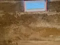 Feuchte Wände im Keller eines alten Hauses, deutet auf Grundwasser im Keller hin. Ein kleines Fenster ist sichtbar.