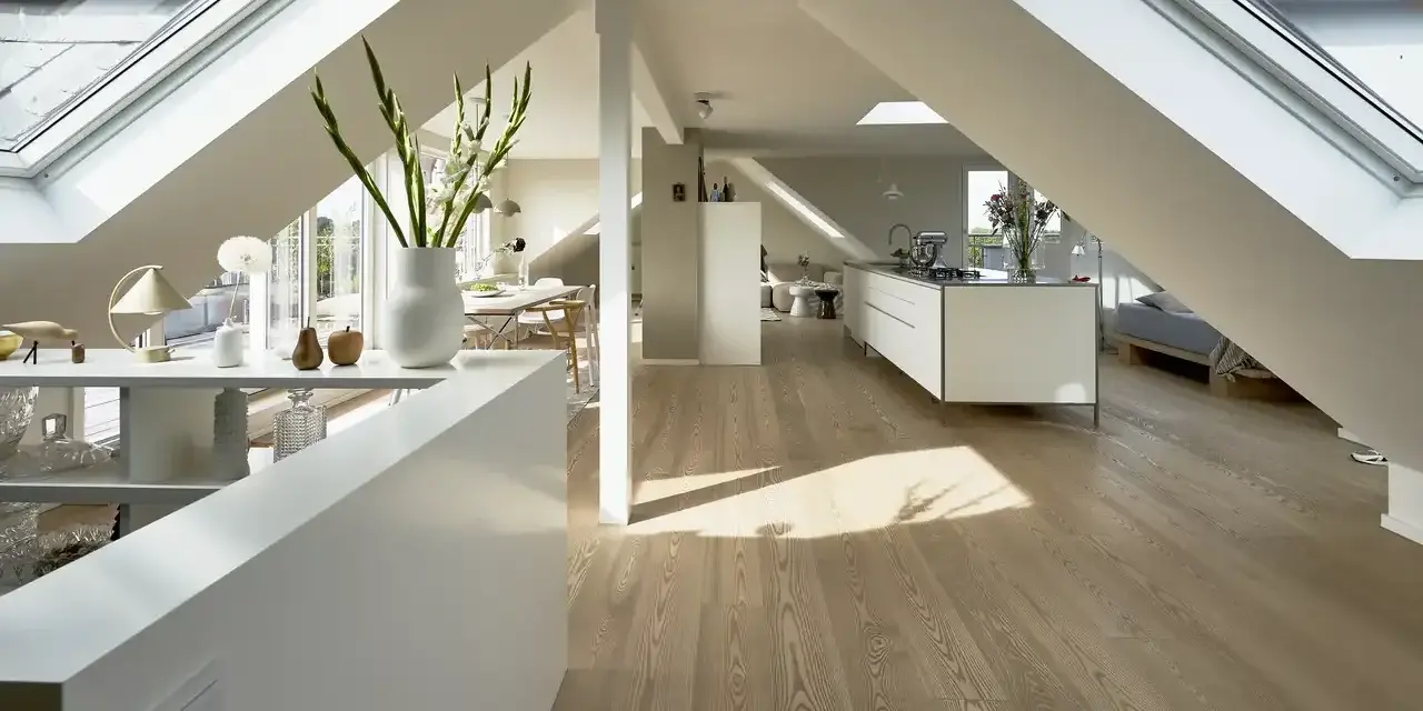 Heller, moderner spitzboden ausbauen mit Dachfenstern, offener Küche und Essbereich. Holzboden und weiße Möbel schaffen ein luftiges Ambiente.