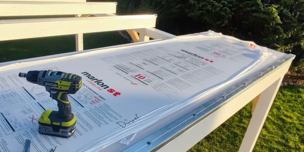 Werkzeug liegt bereit, um Hohlkammerplatten zu schneiden. Ein Akkuschrauber, Cutter und Schrauben auf der neuen Überdachung.