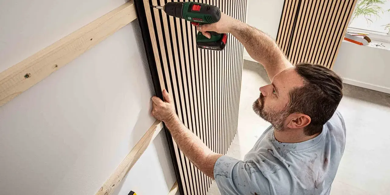 Mann montiert Akustikpaneele an Wand. Tolle Ideen für moderne Raumgestaltung und Schallschutz.