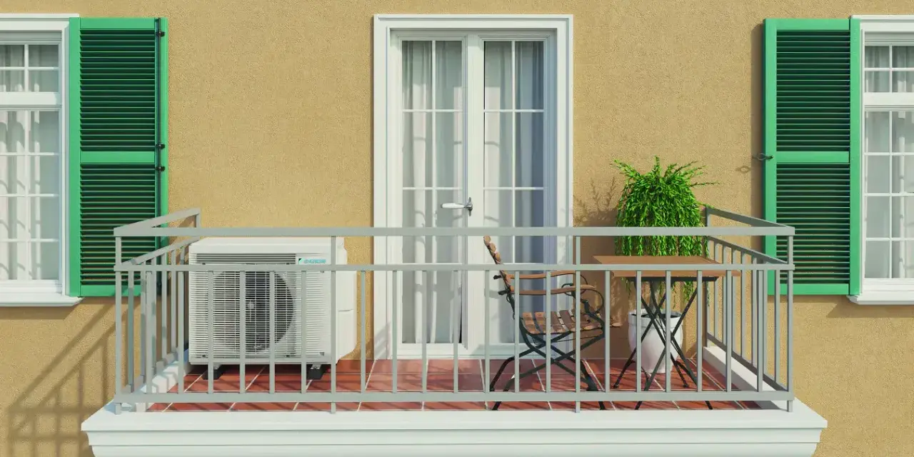 Balkon eines Mehrfamilienhauses mit Klimaanlage, Tisch und Stuhl. Grüne Fensterläden und eine Tür mit Vorhängen.