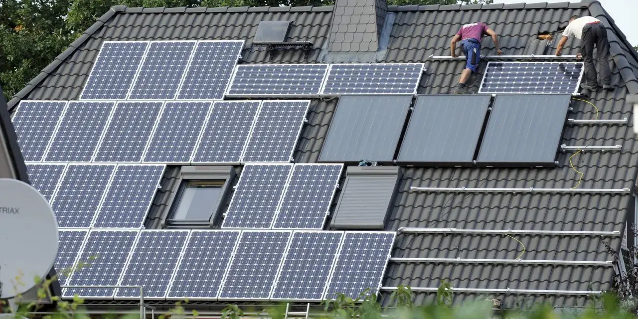Arbeiter installieren eine PV-Anlage nach 20 Jahren auf einem Dach.