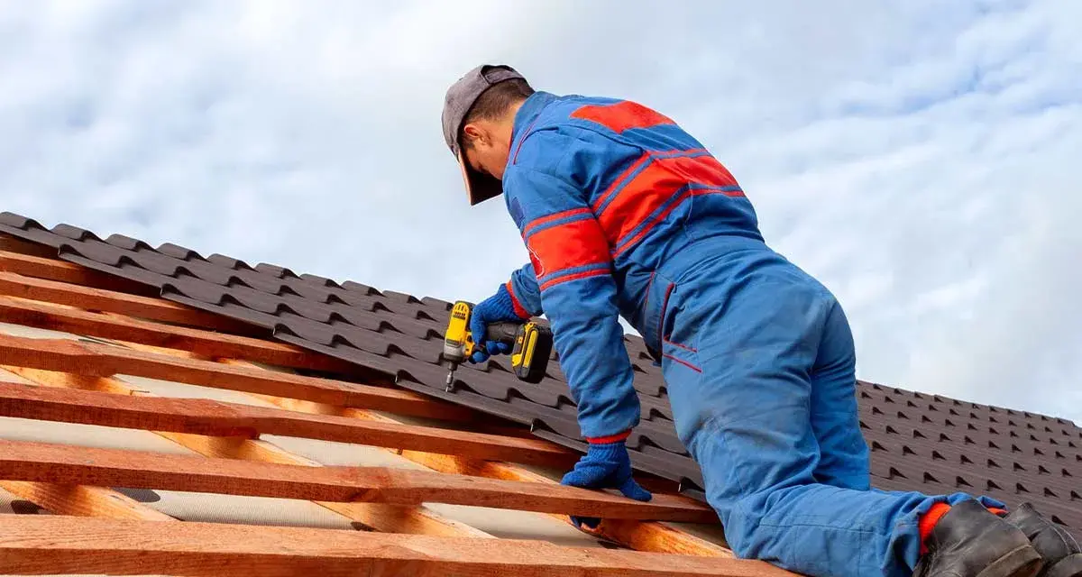 Handwerker montiert mit Akkuschrauber neue Dachziegel. Informieren Sie sich über die **Blechdach Kosten** für Ihr Projekt.