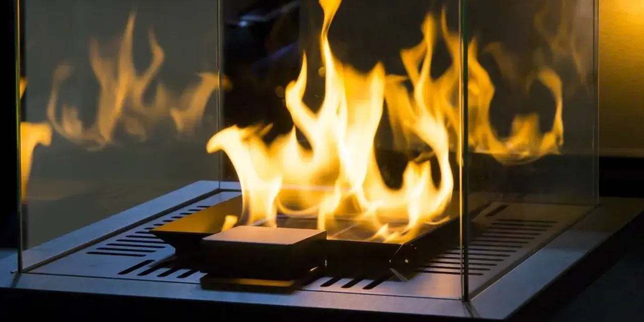 Flammen tanzen in einem modernen, gläsernen Kamin. Ein stilvoller holzofen ohne schornstein, der Wärme und Gemütlichkeit ausstrahlt.