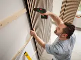 Mann montiert Akustikpaneele an Wand. Tolle Ideen für moderne Raumgestaltung und Schallschutz.