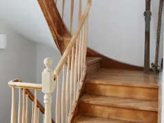 Eine alte Holztreppe wartet auf ihre Renovierung. Die Stufen und das Geländer aus hellem Holz zeigen Gebrauchsspuren, bereit für ein neues Leben.