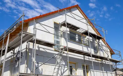 Haus mit Gerüst für Fassadensanierung. Die Kosten für eine Fassadensanierung können stark variieren.
