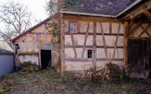 Ein altes Fachwerkhaus wartet auf seine Sanierung. Die Holzbalken und Lehmwände zeigen deutliche Spuren der Zeit.