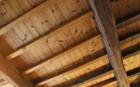 Holzbalkendecke sanieren: Alte Holzbalken und Holzbretter bilden eine rustikale Decke, die bereit für eine Sanierung ist.