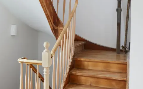 Eine alte Holztreppe wartet auf ihre Renovierung. Die Stufen und das Geländer aus hellem Holz zeigen Gebrauchsspuren, bereit für ein neues Leben.