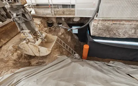 Bagger gräbt Baugrube für Kellerabdichtung. Kosten für Keller trocken legen sind hier sichtbar.