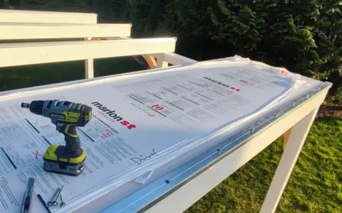 Werkzeug liegt bereit, um Hohlkammerplatten zu schneiden. Ein Akkuschrauber, Cutter und Schrauben auf der neuen Überdachung.