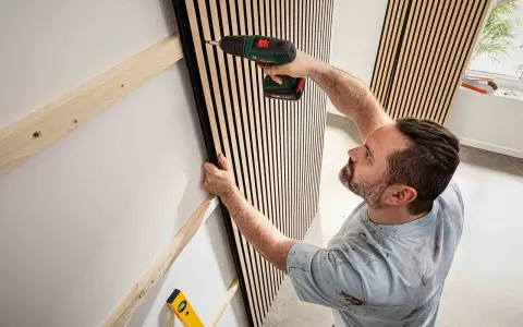 Mann montiert Akustikpaneele an Wand. Tolle Ideen für moderne Raumgestaltung und Schallschutz.