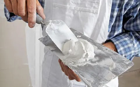 Hand mit Spachtel und Spachtelmasse für die q4 Spachtelung.