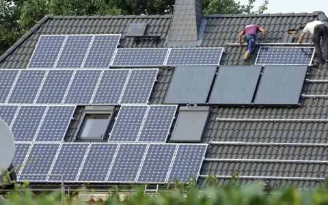 Arbeiter installieren eine PV-Anlage nach 20 Jahren auf einem Dach.