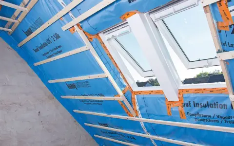 Konterlattung auf blauer Dampfbremse, die für die Dachisolierung vorbereitet wird. Dachfenster sind eingebaut.