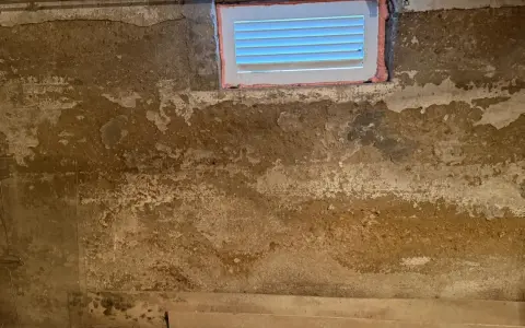 Feuchte Wände im Keller eines alten Hauses, deutet auf Grundwasser im Keller hin. Ein kleines Fenster ist sichtbar.