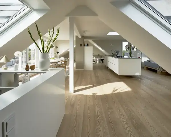 Heller, moderner spitzboden ausbauen mit Dachfenstern, offener Küche und Essbereich. Holzboden und weiße Möbel schaffen ein luftiges Ambiente.