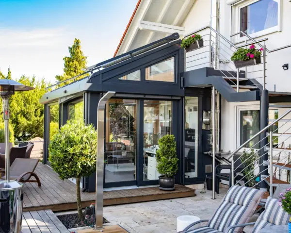 Moderner Wintergarten mit Außentreppe und Terrassenmöbeln. Ein Heizpilz sorgt für Wärme.