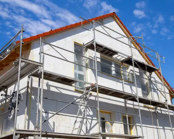 Haus mit Gerüst für Fassadensanierung. Die Kosten für eine Fassadensanierung können stark variieren.
