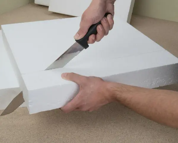 Hände schneiden mit einem Messer präzise Styropor für ein Bastelprojekt.