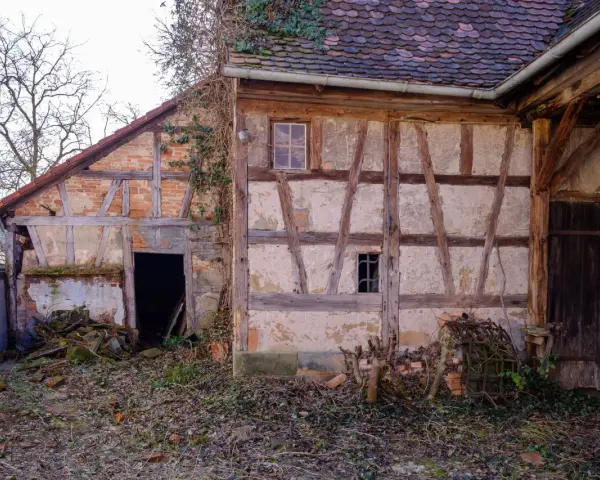 Ein altes Fachwerkhaus wartet auf seine Sanierung. Die Holzbalken und Lehmwände zeigen deutliche Spuren der Zeit.