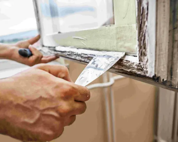 Hände entfernen mit Spachtel alten Fensterkitt. Vorbereitung für das Fensterkitt erneuern.