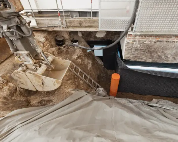 Bagger gräbt Baugrube für Kellerabdichtung. Kosten für Keller trocken legen sind hier sichtbar.