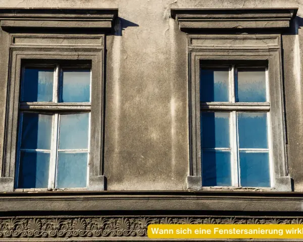 Zwei alte Fenster mit blauen Scheiben an einer verwitterten Fassade. Eine energetische Sanierung der Fenster würde sich hier lohnen.